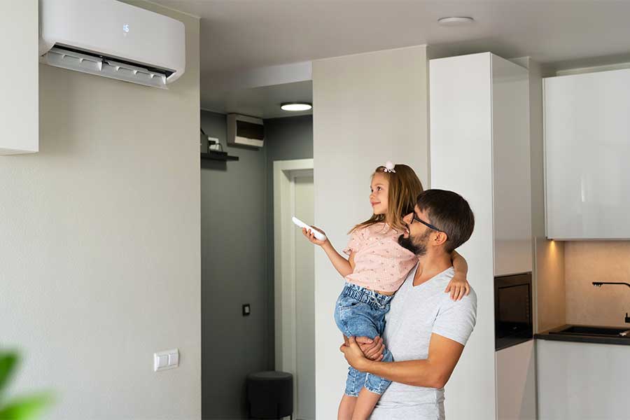 dad holding up daughter to adjust ductless ac